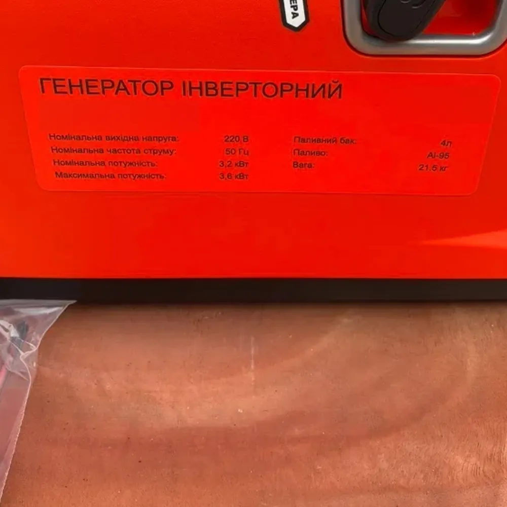 Шильдик на помаранчевому корпусі: генератор інверторний, напруга 220 В, частота 50 Гц, номінальна потужність 3,2 кВт, максимальна 3,6 кВт, паливний бак 4 л, паливо АІ-95, вага 21,5 кг